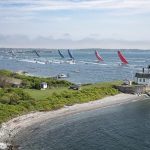 A line of colorful sailboats carried on the wind of Newport Harbor