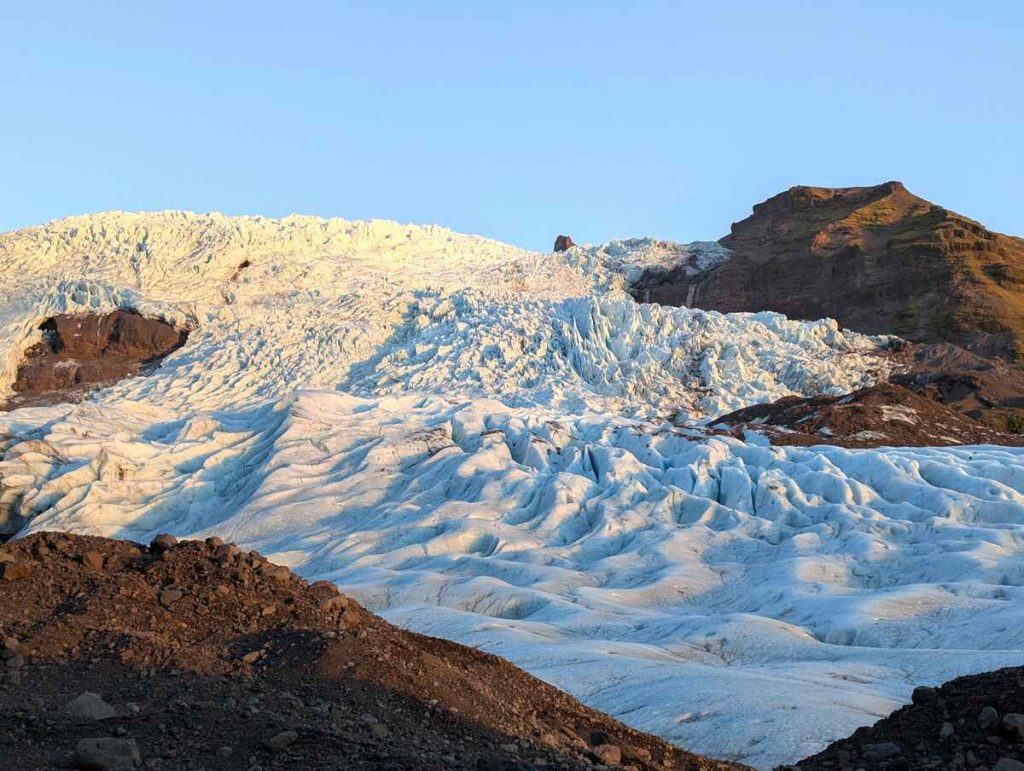 Undulating waves of snow and ice lead up the side of a glacier as part of Iceland travel