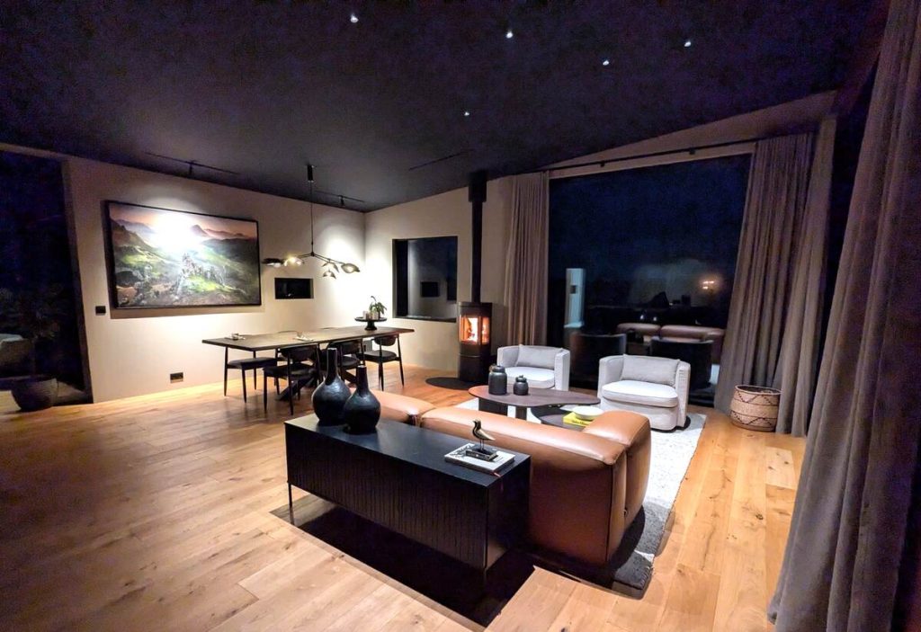 A sleek, modern living room and dining room with leather and upholstered furniture and polished wood floors
