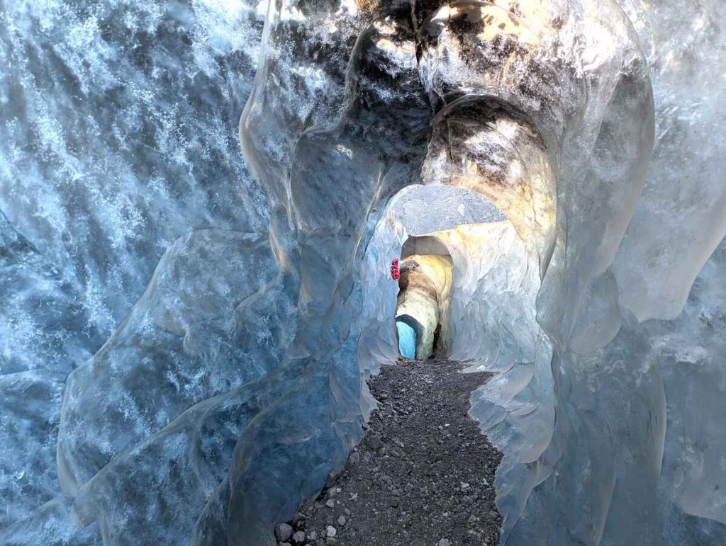 The wavy blue and white walls and irregular tunnel opening of a an Icelandic ice cave