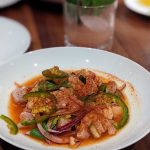 White plate with seafood ceviche and a cocktail in the background
